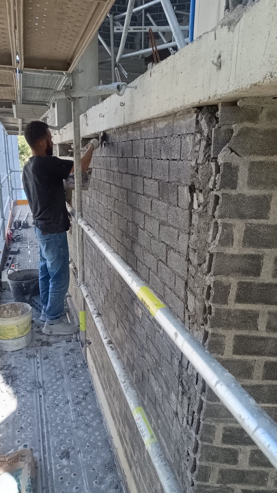 Operario enfoscando muro de bloque en fachada