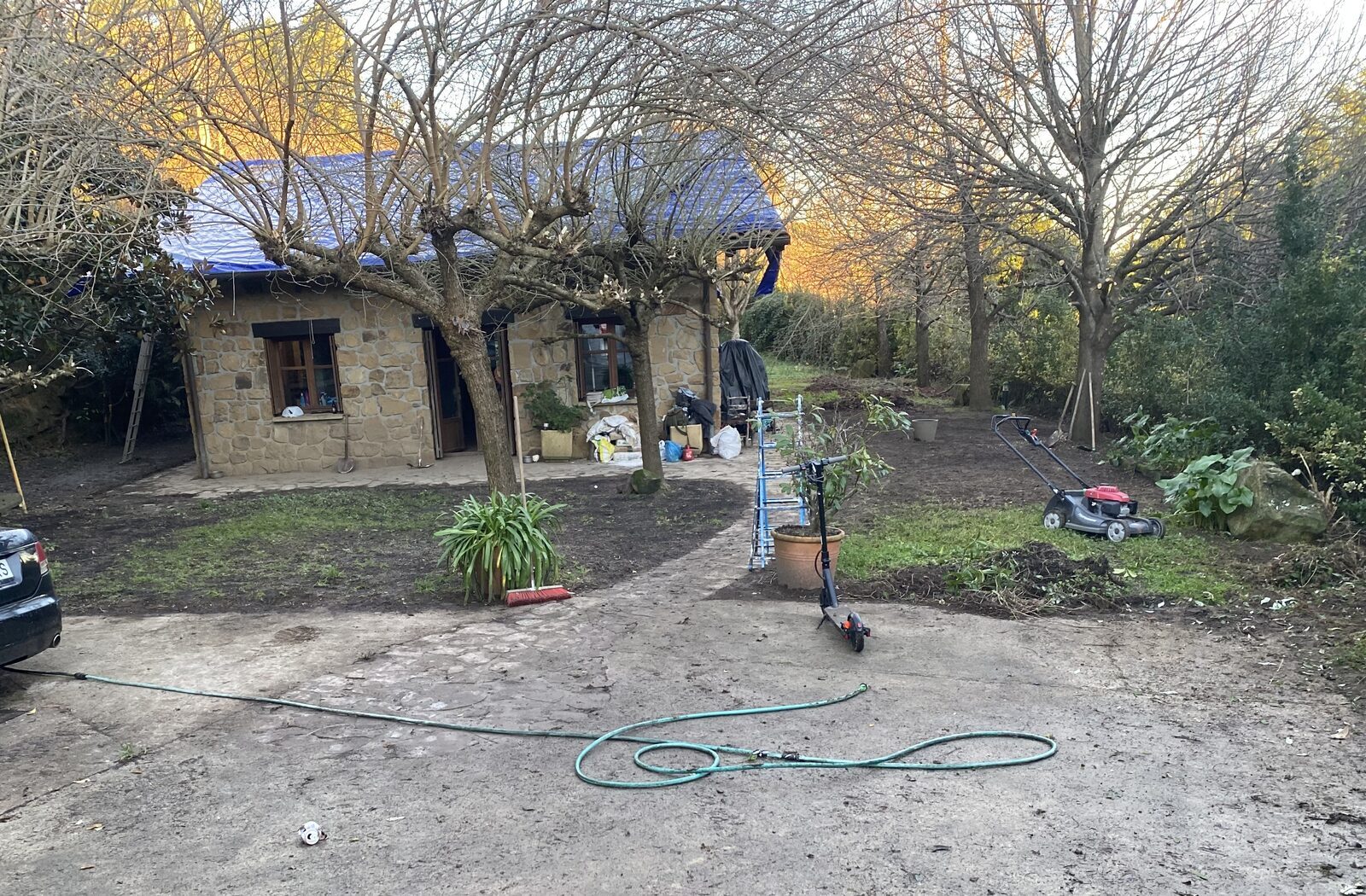 Vivienda de piedra con cubierta protegida y jardín antes del desbroce