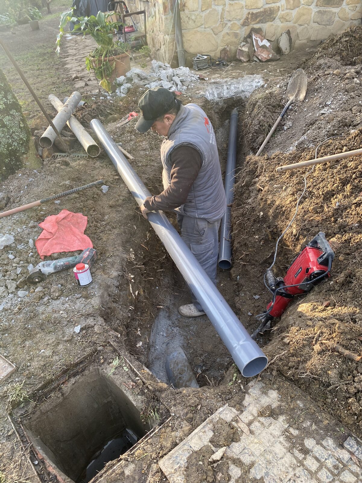 Operario conectando bajante de gran diámetro junto a muro de piedra
