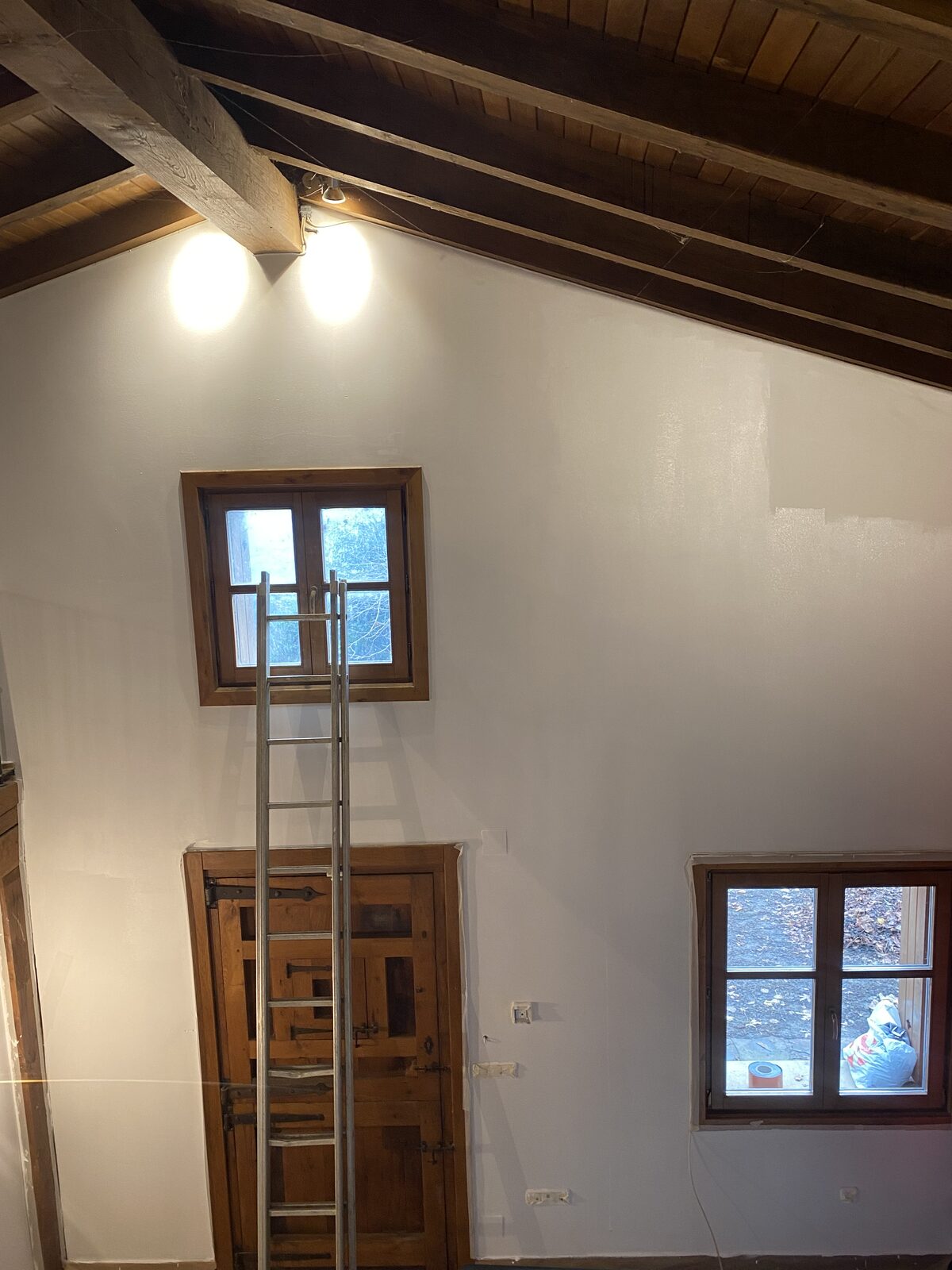 Paredes recién pintadas de blanco en buhardilla con vigas de madera